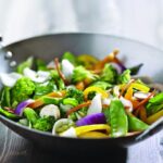 A mixed vegetable stir fry in a large wok.